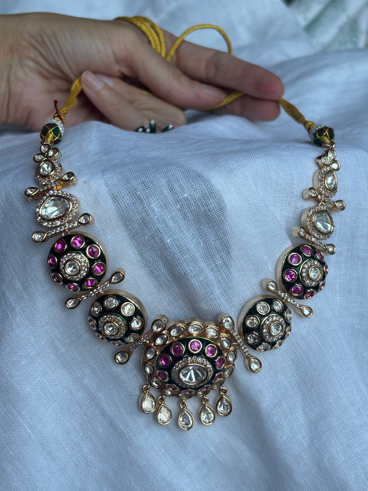Decorative bracelet with gemstones held by a hand against a light fabric background