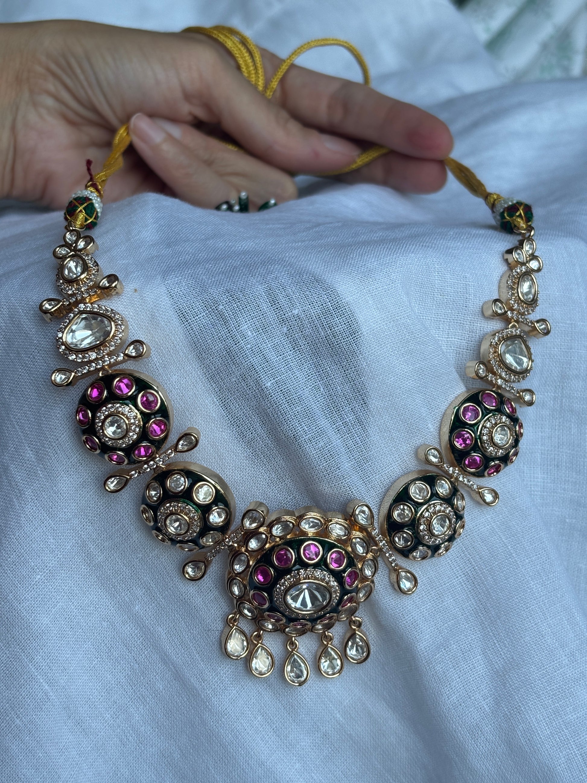 Decorative bracelet with gemstones held by a hand against a light fabric background